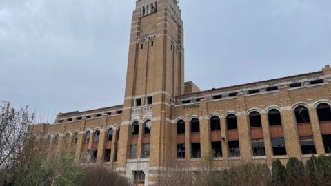 An abandoned brick building with a tower in the center and no windows