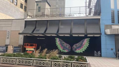 A one story building with bright wings painted on the front
