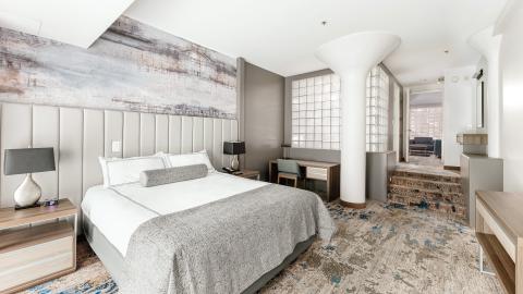 A hotel room with a king sized bed and muted tones