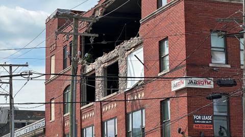 A 4-story brick building with a large hole on the 4th floor
