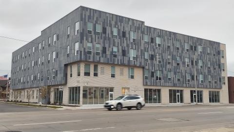 A three-story grey new apartment building